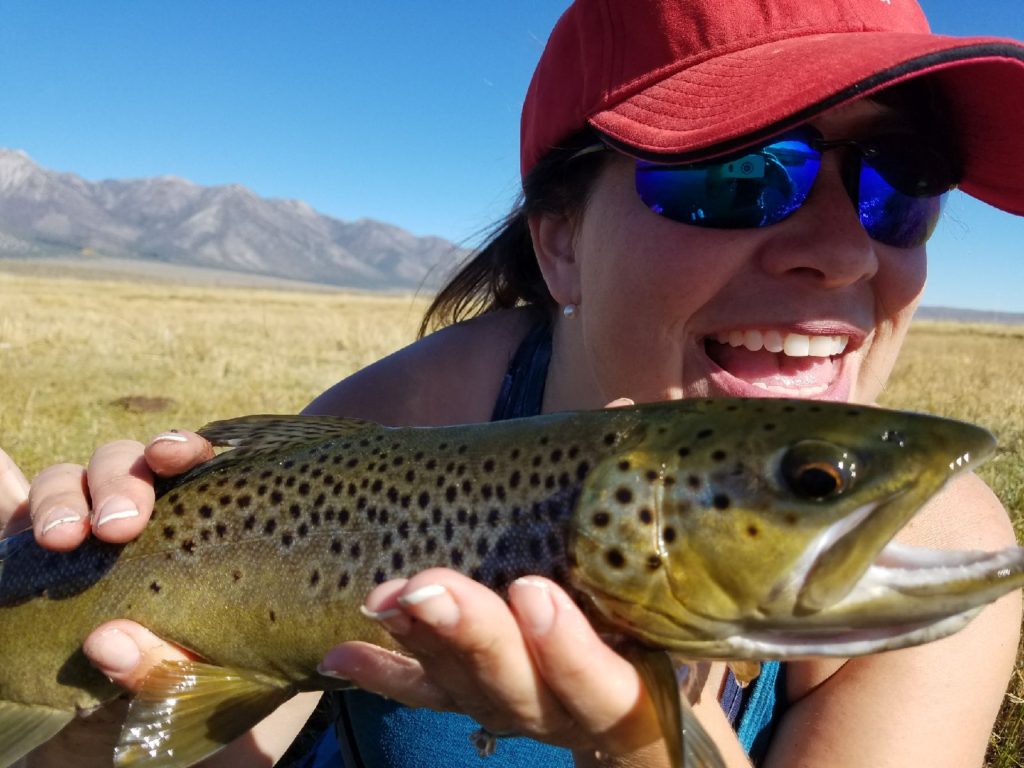 Happy female angler holds a large brown trout 