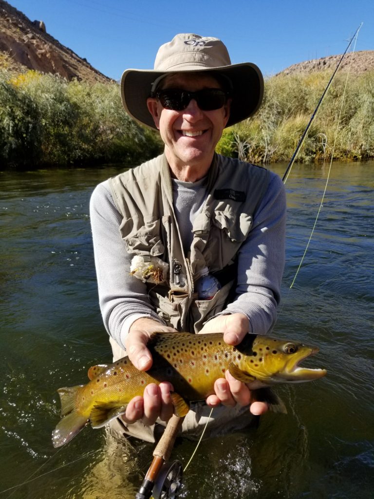Larger brown trout held by happy angler on lower Owens River in Bishop CA STM Fly Shop