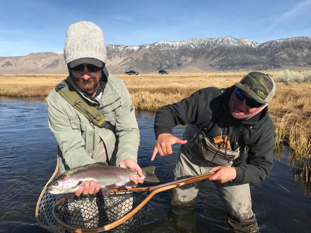 fishing guide helps client land a large trout on the Upper Owens River