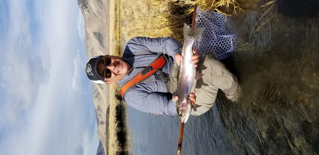 gentleman hold a large rainbow trout on the banks of the Upper Owens River Near Mammoth Lakes CA