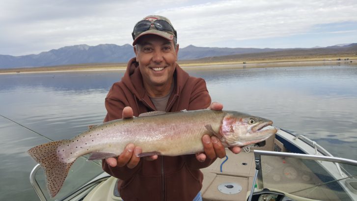 Crowley lake Fly Fishing angler holds a large fish over the boat on Crowley Lake