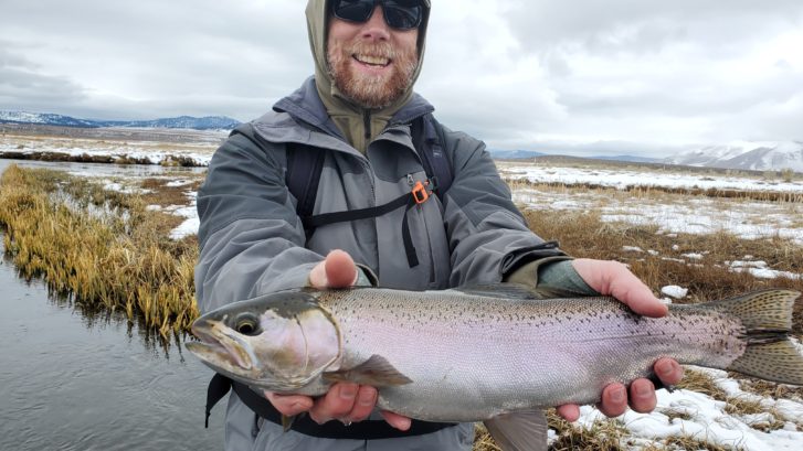 Very fat large Trout held above partly snowy ground on the Upper Owens River near Mammoth Lakes CA