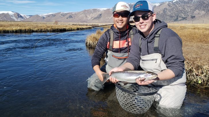Father and Son pose with a trout over the Upper Owens River near Mammoth Lakes California