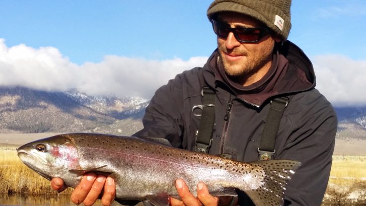 Angler Holds a fat Rainbow Trout above the Upper Owens River below Mammoth Lakes California