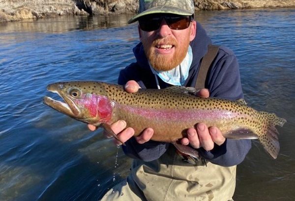 red beard holds a nice rainbow trout above the water of the Lower Owens River near Bishop, CA