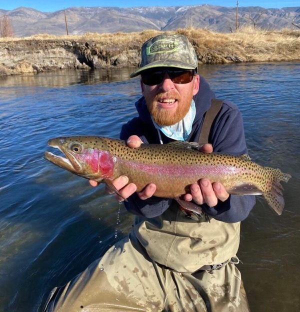 red beard holds a nice rainbow trout above the water of the Lower Owens River near Bishop, CA