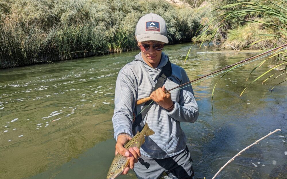 young man holds a fish above the Lower Owens water near Bishop california